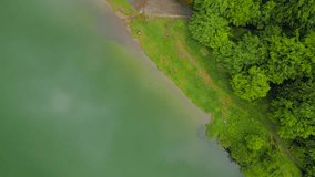 Aerial footage of Saint Ann volcanic lake located In Romania. Video was taken from a drone at high altitude with the camera pointing straight down for a top view of the boats moored to the pier.