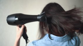 The girl dries her hair with a hairdryer. Concept of well-groomed and beautiful woman. Close up video of Woman drying hair using black hair dryer.