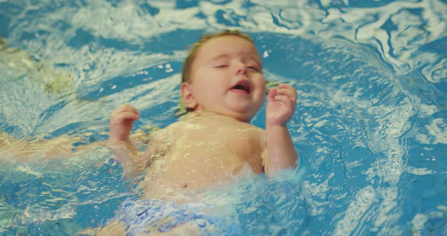 Father holding little baby and helping to swim in swimming pool with clean blue water. Professional water therapy for kids . Swimming training from an early age . Parent having fun . Happy lifestyle Royalty-Free Stock Footage #1101622361