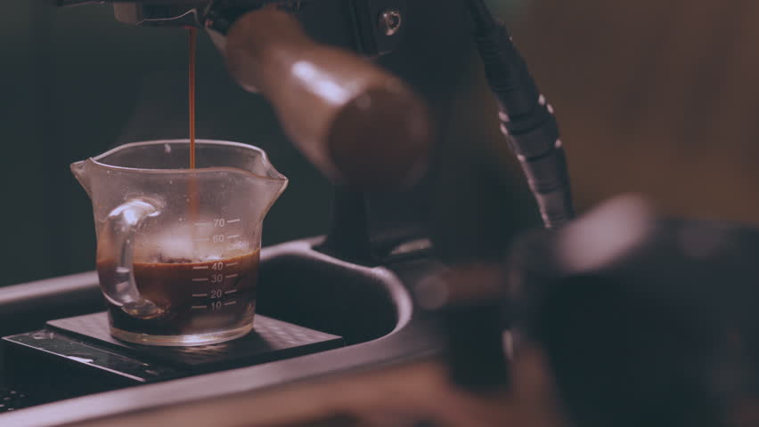 Close up slow motion 4K of beautiful coffee liquid flowing from coffee machine into clear glass on barista counter in coffee shop shows concept of enjoyment beverage for breakfast in the morning. | Shutterstock HD Video #1101623099