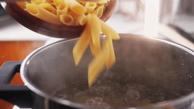 Male chef adding penne pasta into boiling water in pot.  - Powered by Shutterstock - Get 15% off with code: PIKWIZARD15