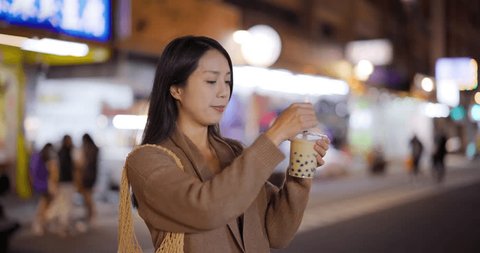 Woman enjoy bubble milk tea in street market of Taiwan Arkistovideo