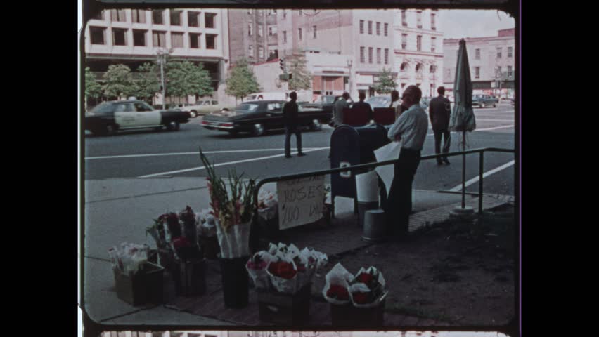 1974 Washington, DC. Retro street scene with flower vendor and 1970s style taxi on the National Mall. Capitol building can be seen at distance. 4K Overscan of vintage archival newsreel film