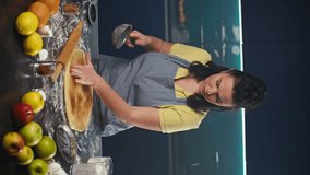 Woman cook prepares pie dough in the kitchen. A girl in an apron adds cinnamon to the dough. Vertical video. High quality 4k footage