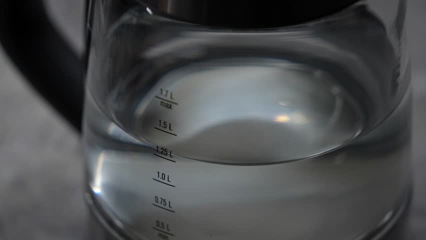 Electric glass kettle boils water. Measuring column, the amount of water. Slow motion teapot. Boiling process. Close-up, gurgling hot water, teapot lighting | Shutterstock HD Video #1101631575