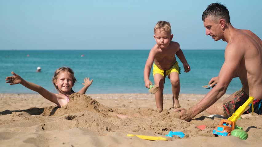 Children play with their father on the beach with sand. The family had fun at the seaside.

 Royalty-Free Stock Footage #1101632931