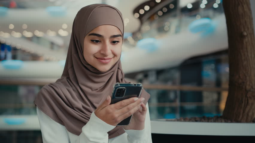 Arabian muslim woman student girl in hijab look at mobile phone screen shopping online store use digital apps win internet discount happy smiling businesswoman customer shopper make order e-commerce Royalty-Free Stock Footage #1101633261