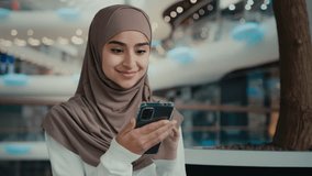 Arabian muslim woman student girl in hijab look at mobile phone screen shopping online store use digital apps win internet discount happy smiling businesswoman customer shopper make order e-commerce