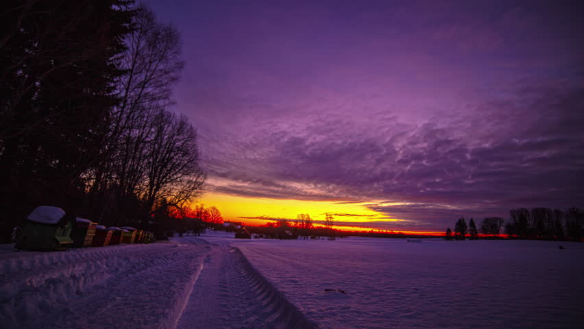 Timelapse of rising sun in sky over snowy landscape at sunrise. Night to day