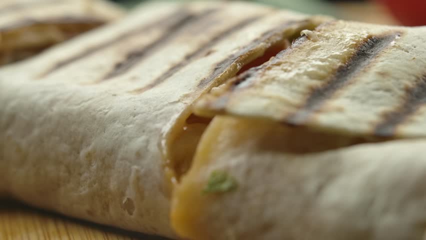 Sliced piece of burrito rises to reveal an appetizing slice of stretchy cheese Royalty-Free Stock Footage #1101634641