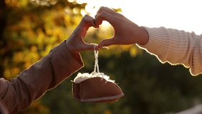 Man and pregnant wife are doing heart gesture with hands and holding warm baby shoes on nature autumn background. Future parents waiting for the baby. The concept of Mother's Day and Women's Day - Powered by Shutterstock - Get 15% off with code: PIKWIZARD15