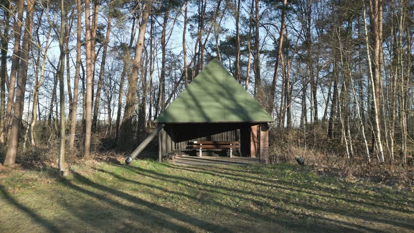 A zoom out drone shot of a cabin in the woods in front a lake with ducks in it