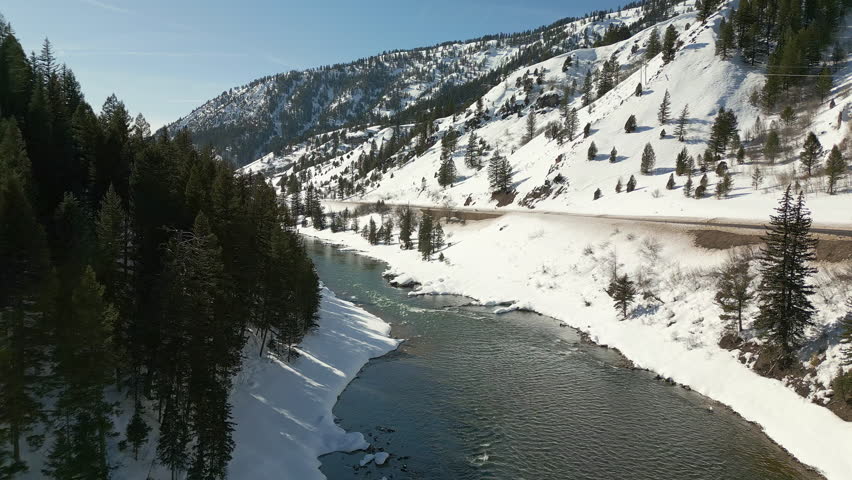 Flying through winter landscape down towards the Snake River flowing downstream in Wyoming.