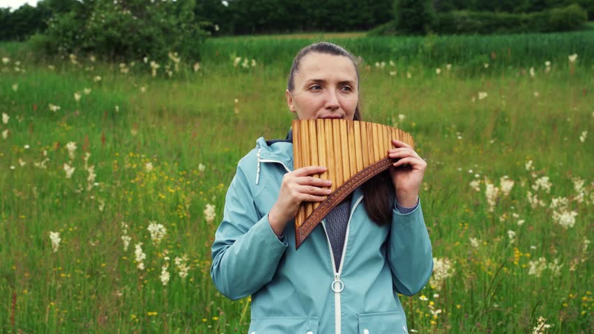 A young woman plays the pan flute in nature Royalty-Free Stock Footage #1101639269