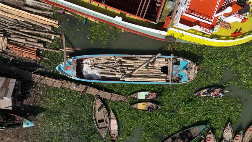Men roll the logs from the ship to the sea using primitive methods. Dhaka city center, Bangladesh.