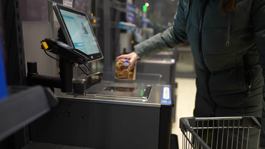 the girl scans the goods at the self-service checkout and pays for the purchase using the phone Royalty-Free Stock Footage #1101640025