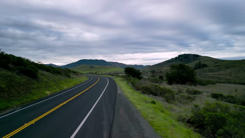 Open road through green hills and reservoir in Northern California landscape Royalty-Free Stock Footage #1101640155
