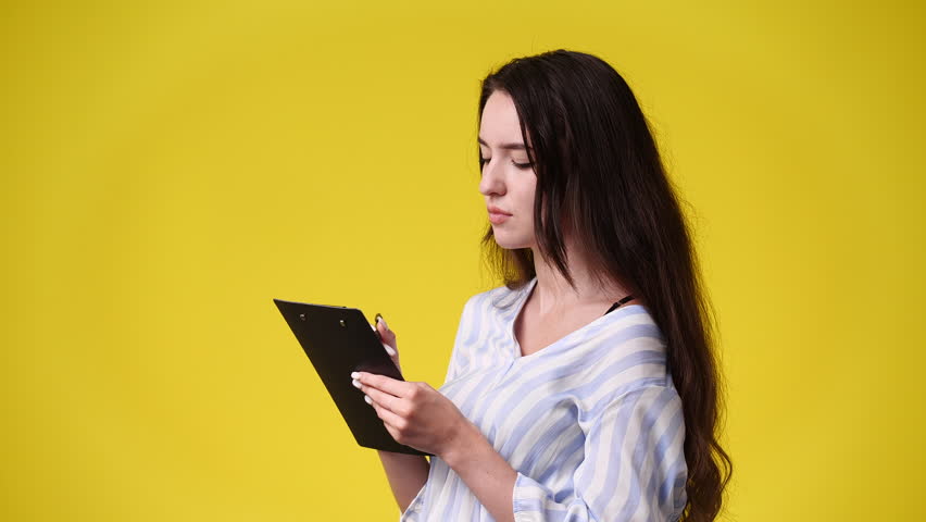 4k video of one girl taking down some notes over yellow background. | Shutterstock HD Video #1101641433