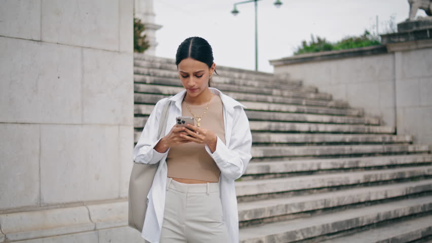 Nervous woman typing cellphone fast outdoors. Worried student girl feeling lost looking around on street. Stressed latina businesswoman checking notifications on smartphone. Confused lady getting sms  Royalty-Free Stock Footage #1101643391