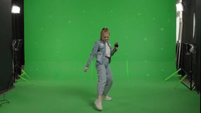 Attractive girl sings into a microphone and moves to the beat of music on Green screen. Young white woman having fun at karaoke - Powered by Shutterstock - Get 15% off with code: PIKWIZARD15