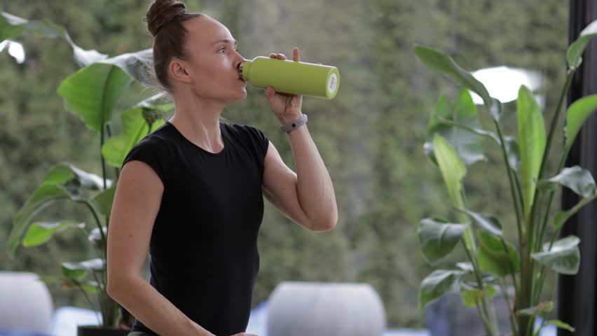 Caucasian woman is drinking water after workout.