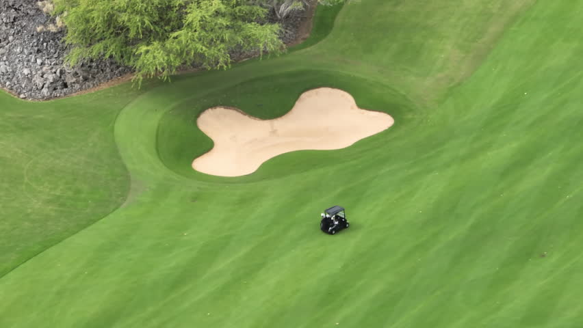 Aerial footage of people on a golf course playing the sport match on Big Island, Hawaii, USA. Cinematic overhead view on active men playing the golf game on a sunny summer day. Background for business