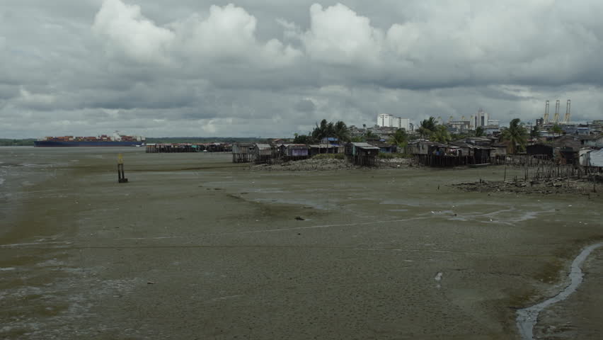 Wide angle of a container ship in the distance passing by a poor neighborhood in Buenaventura, Colombia.