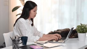 Focused young woman small business entrepreneur typing on laptop keyboard while working at home office
