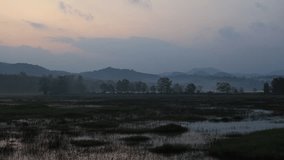 The background of a high-angle video with panoramic views of rivers, mountains, and passing clouds in a blurred way, as the sun sets again for another day.