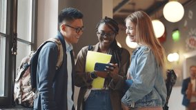 Multiethnic young college students using smartphone in corridor. Diverse friends look at cellphone and laugh in university hallway. Man and women use mobile phone together. Realtime - Powered by Shutterstock - Get 15% off with code: PIKWIZARD15