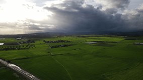 Clouds hung in the interim over the green fields. They portend a dramatic storm as they move across the plains. Bird's eye view. Cyprus. Real-time UHD 4K video.