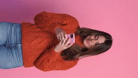Smiling woman in sweater taking selfie. Vertical video.