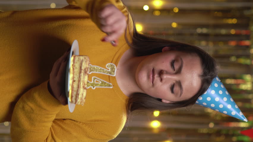 Beautiful happy young woman wearing sweater holding birthday cake number 74 golden candles burning by lighter. Concept of celebrating birthday and anniversary. POV.