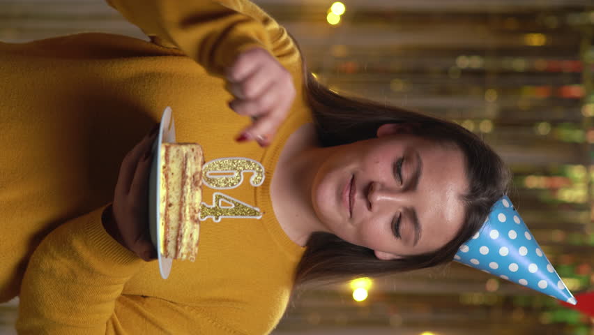 Beautiful happy young woman wearing sweater holding birthday cake number 64 golden candles burning by lighter. Concept of celebrating birthday and anniversary. POV.