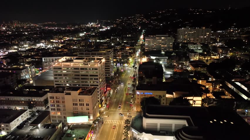 Establishing aerial view of Hollywood neighborhood at night over congested Los Angeles of buildings and traffic