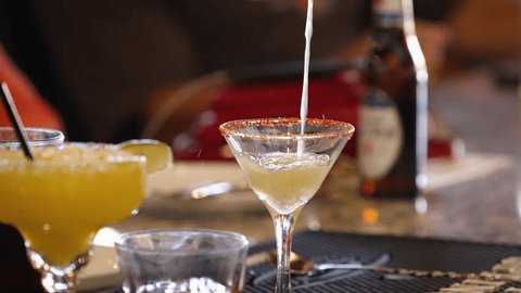 Стоковое видео: Bartender pours Mexican martini from shaker into a dressed glass, slow motion 4K