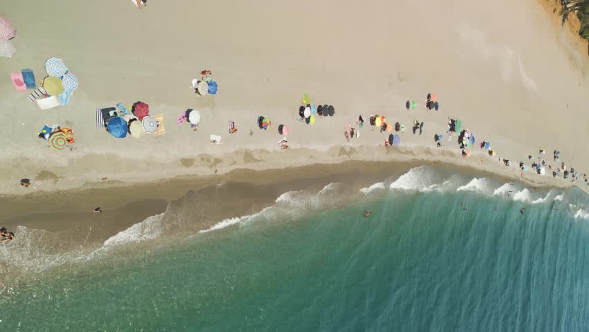Vertical aerial view of people on the beach in summertime, Sicily, Italy.