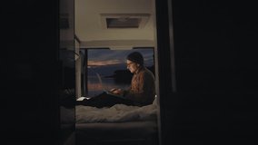 Urban digital nomad of millennial generation working on a laptop in the camper van by the seaside at sunset. Creative working inspired by the nature. Remote office job.  - Powered by Shutterstock - Get 15% off with code: PIKWIZARD15