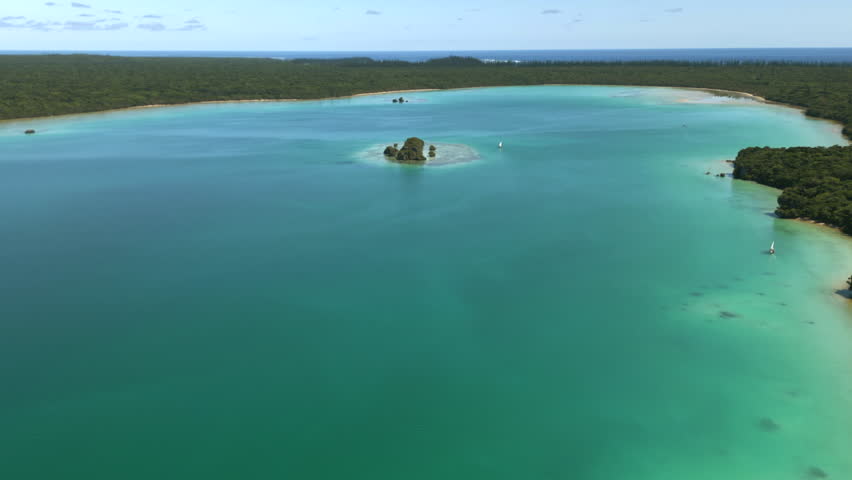 Traditional pirogues on pristine waters of Upi Bay, Isle of Pines in New Caledonia - pull back aerial reveal