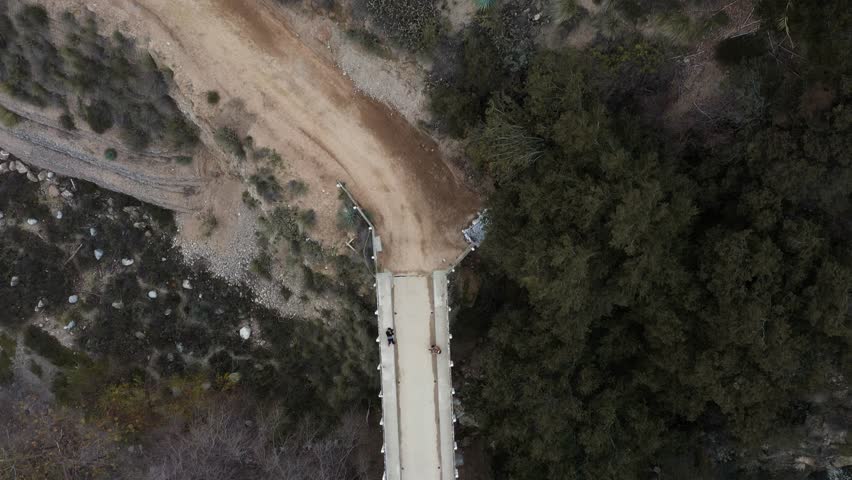 Chuck Ballard Memorial Bridge looking into Eaton Canyon Falls trail in Angeles National Forest in Pasadena, California. Aerial pan tilt orbit.