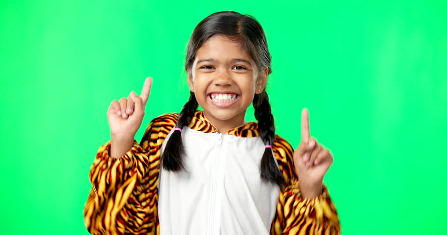 Face, dancing and girl with green screen, pointing up and happiness with joy, cheerful and inspiration. Portrait, young person and female child with direction, decision and options with choice or joy