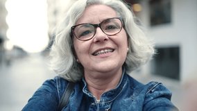 Middle age woman with grey hair smiling confident having video call at street