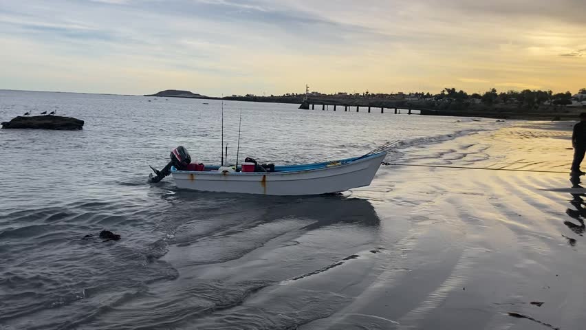 Flat bottom motorboat is dragged ashore by SUV and fishermen