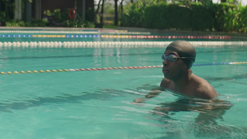 Slow motion shot of black male athlete in goggles and cap swimming breaststroke while practicing in outdoor pool on summer day Royalty-Free Stock Footage #1101678153