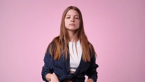 4k slow motion video of one girl who crosses her arms and responds negatively to something over pink background.