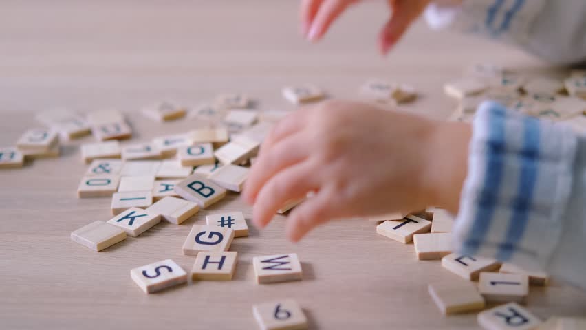 hands close-up, small child 3 years old plays wooden alphabet blocks, makes up words from letters, dyslexia awareness, learning difficulties, human brain development, happy childhood, selective focus