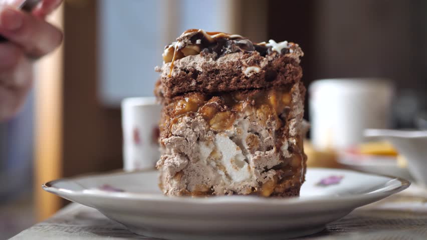 There is a Snickers cake. Bite the cake with a fork. Sweet breakfast. sugar food
