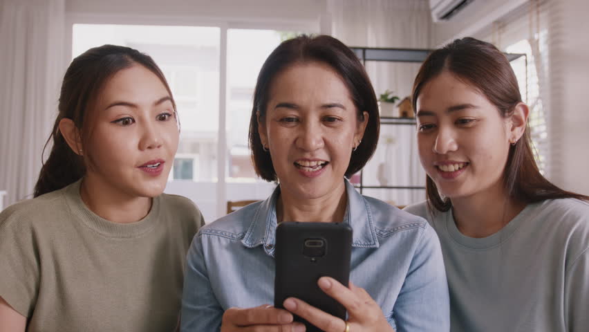 Group of asia people young adult child and middle aged mom looking at mobile phone joy win luck bet online game at home sofa. Senior mum got lucky loan money sale reward on shopping discount promotion Royalty-Free Stock Footage #1101684137