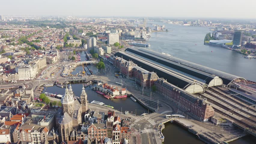 Inscription on video. Amsterdam, Netherlands. Flying over the city rooftops. Amsterdam Central Station. Neon white effect text, Aerial View, Point of interest