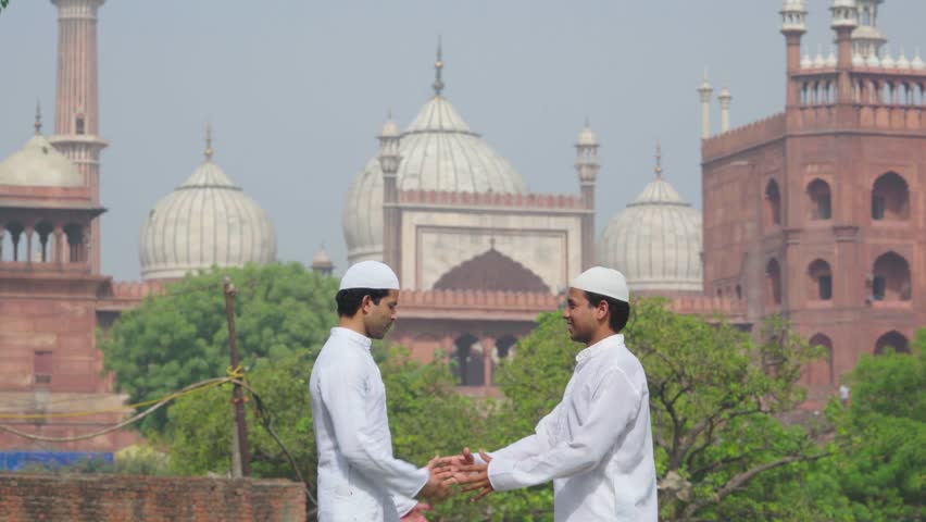 Two Muslim friends greeting and hugging as they meet for celebrating Eid